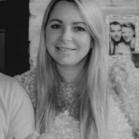 Katie and her family smiling at the camera in a black and white picture. There is Katie, her husband Christian, and their children Ellis and Theia.