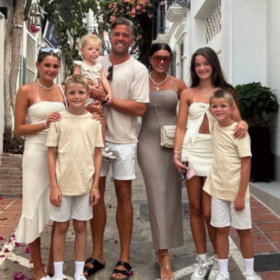 Matt holding his little girl, with his partner beside him and four other children. All wearing white on holiday.