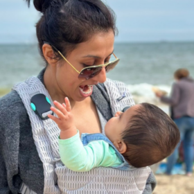 Harpal on the beach with Lara in a carrier.