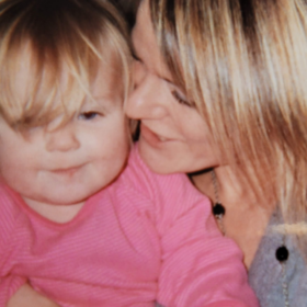 Sue with her daughter sitting on her lap, wearing a pink top.