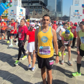 Abs wearing a Lullaby Trust vest, at a running event smiling at the camera.