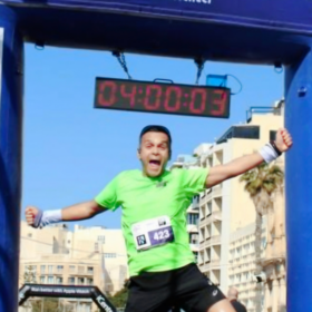 Abs at the finish line of a running event, jumping in the air.