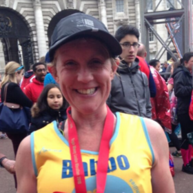 Clare at a running event wearing a medal and a Lullaby Trust vest