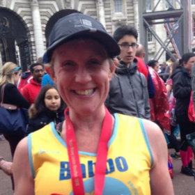 Clare at a running event wearing a medal and a Lullaby Trust vest