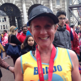 Clare at a running event wearing a medal and a Lullaby Trust vest