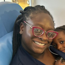 Seyi sitting on a chair with two of her children lying on her.