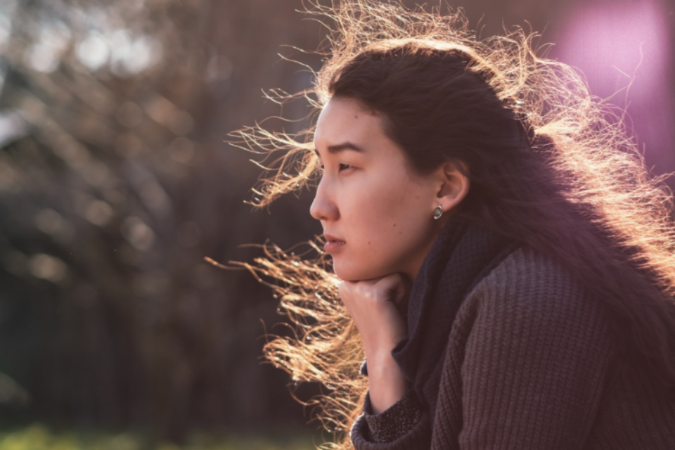 Lady wearing a black coat, sitting outdoors.