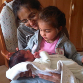 Siya with baby Krishan on her lap. Her mum is behind her.