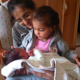 Siya with baby Krishan on her lap. Her mum is behind her.