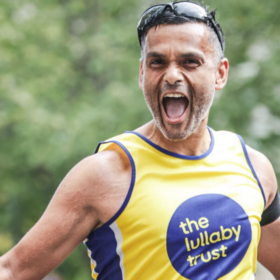 Abs wearing a Lullaby Trust running vest running, with his mouth wide open shouting, looking happy.