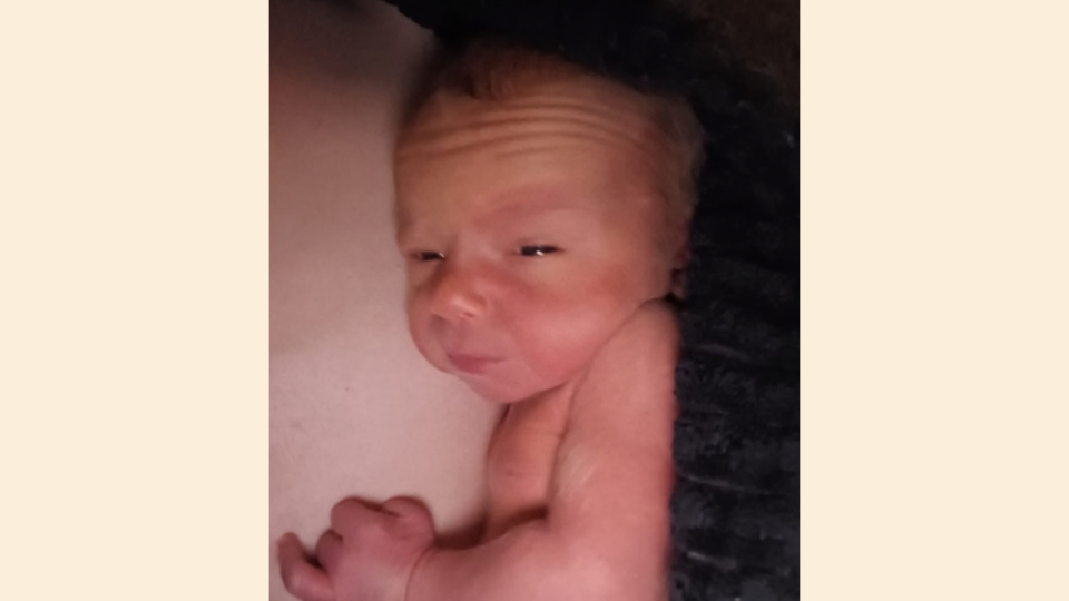 Baby Samuel looking sleepy, resting on his parent.