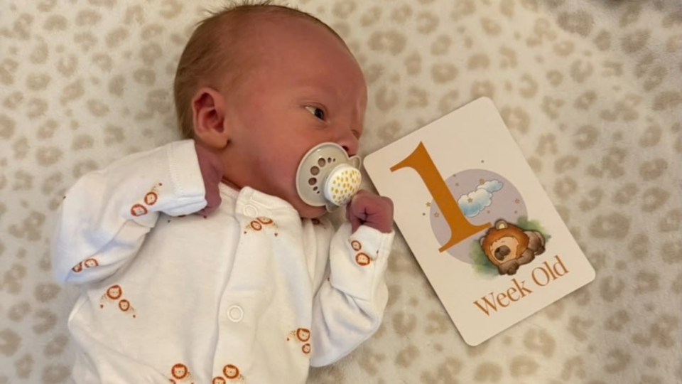 Samuel asleep next to a card that says '1 week old'