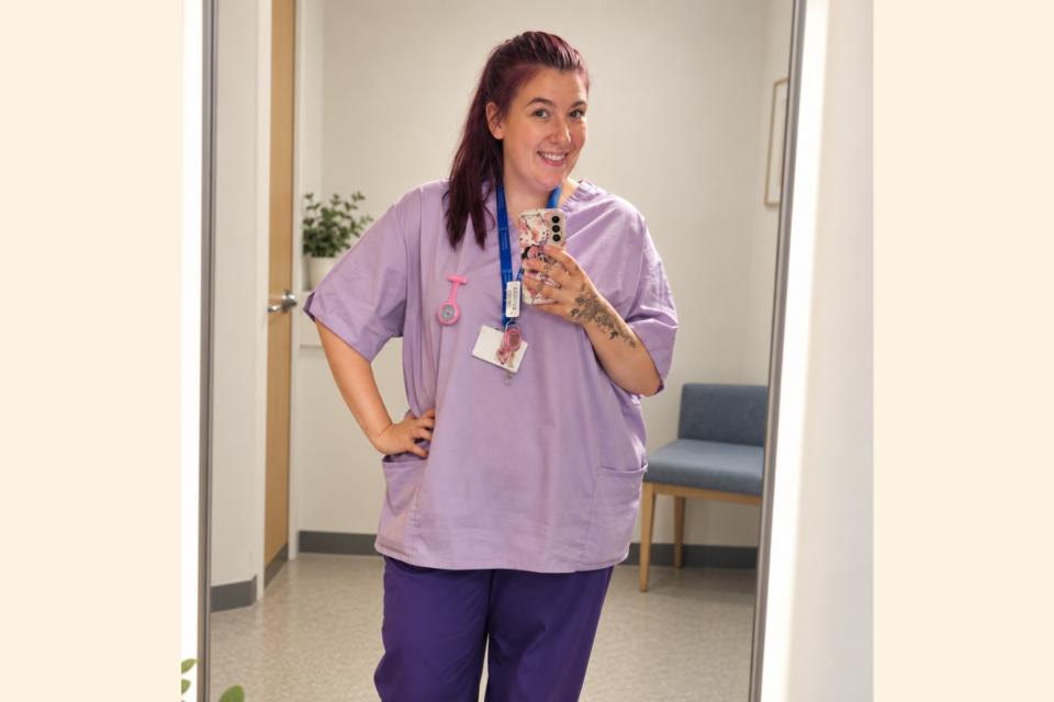 Michaela taking a photo in the mirror, wearing student uniform scrubs.