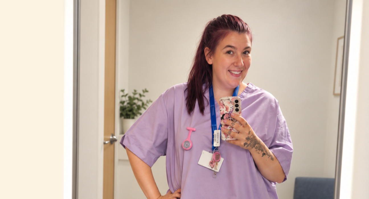 Michaela taking a photo in the mirror, wearing student uniform scrubs.