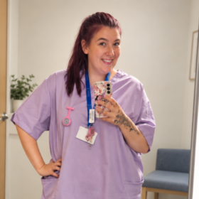 Michaela taking a photo in the mirror, wearing student uniform scrubs.