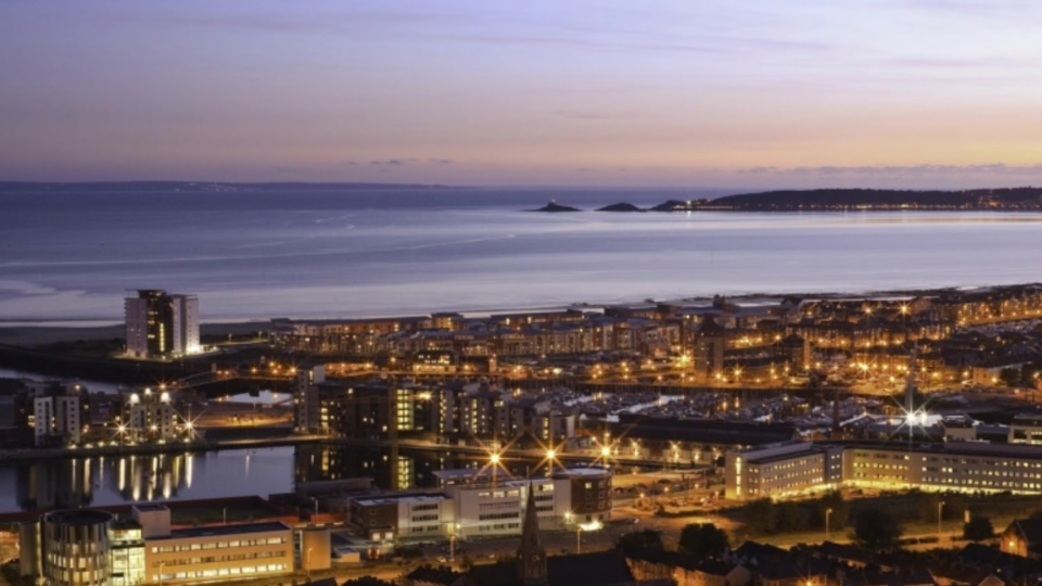 Landscape photo of Swansea's coast at sunset.