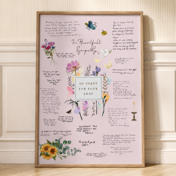 Print in a frame leaning against a wall. The print has a pink background and various messages on it, and illustrations of flowers.