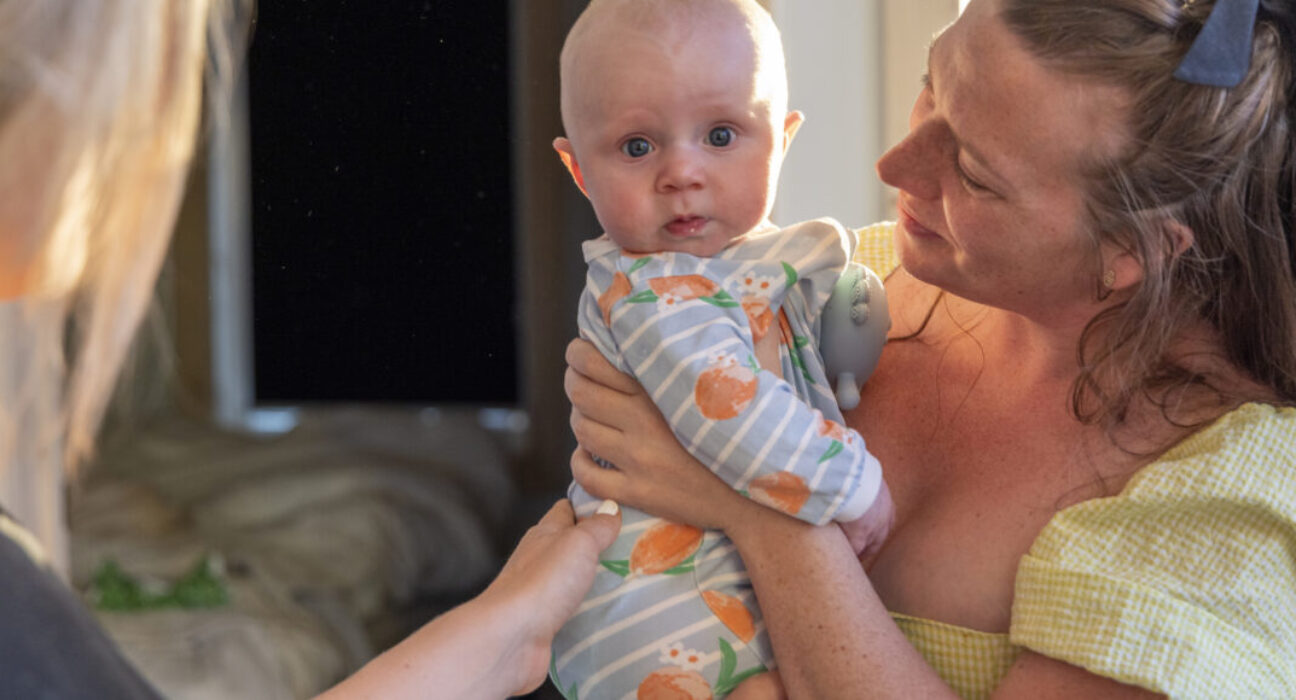 Young women play with newborn baby