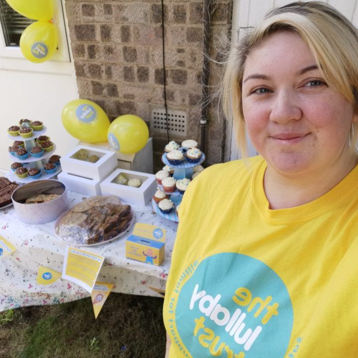 Woman in Lullaby Trust t-shirt in front of bake sale